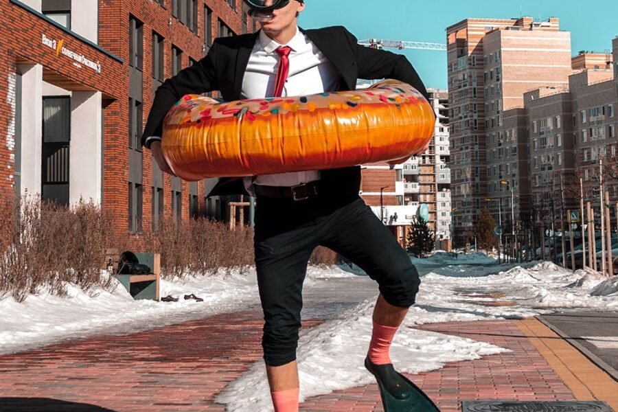 Man in a suit wearing an inner tube walking in flippers in the middle of the winter